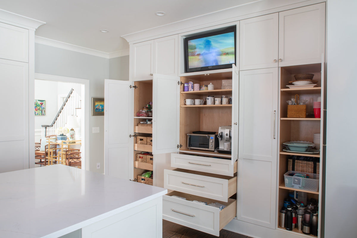 Wall of white cabinetry with doors open to show natural wood interiors, adjustable shelves, roll-out trays, and full-extension drawers