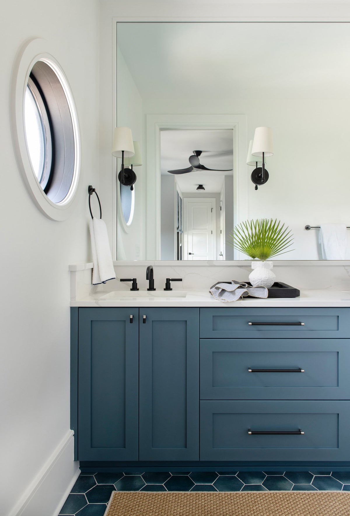 Slate blue shaker vanity with a sink base and three-drawer stack, matte black pulls, a recessed toe kick, and a white quartz top